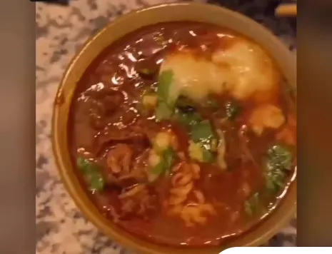 Bowl of birria ramen with shredded beef, noodles, cheese and cilantro