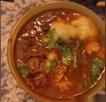 Bowl of birria ramen with shredded beef, noodles, cheese and cilantro